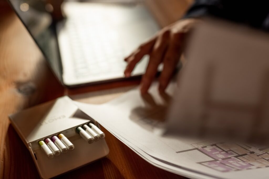 Real estate agent sits at a clean, modern desk, using a calculator to review receipts and documents, illustrating the fina...
