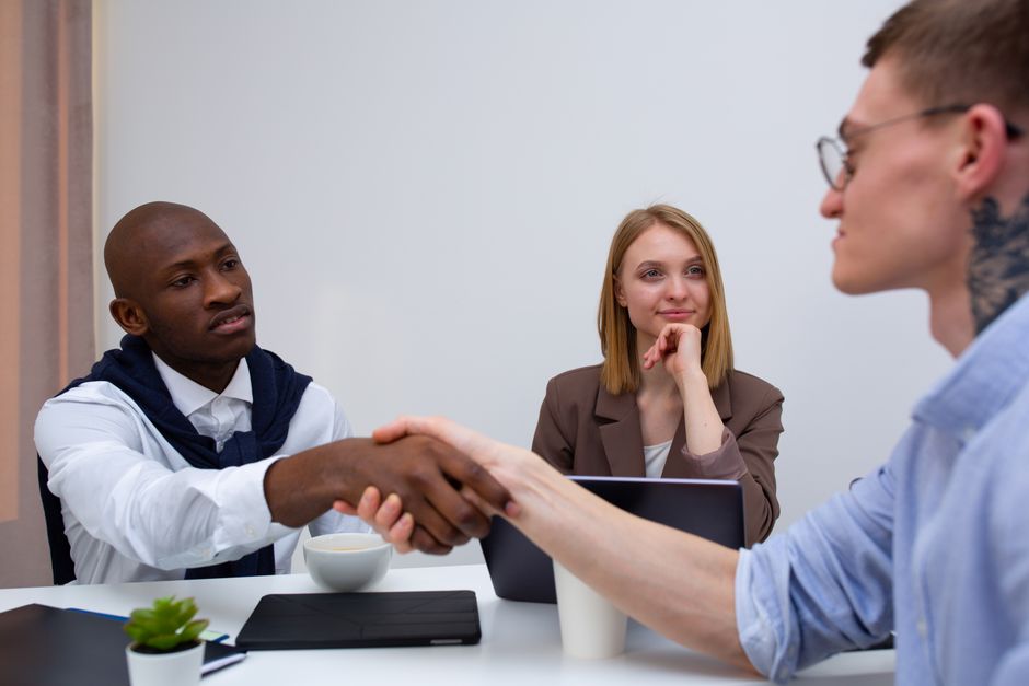 A firm, professional handshake between two people in business attire, symbolizing a successful agreement in a modern office environment.